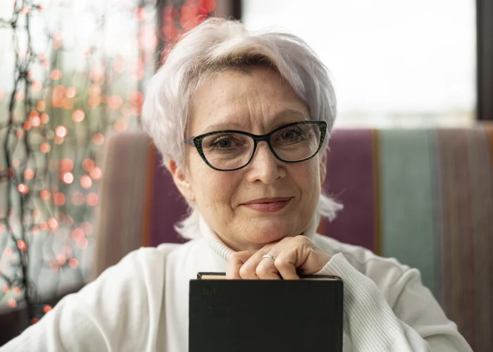 front-view-senior-female-with-glasses-holding-book-min
