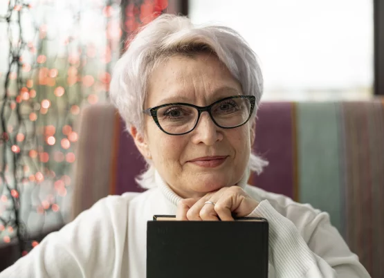 front-view-senior-female-with-glasses-holding-book-min